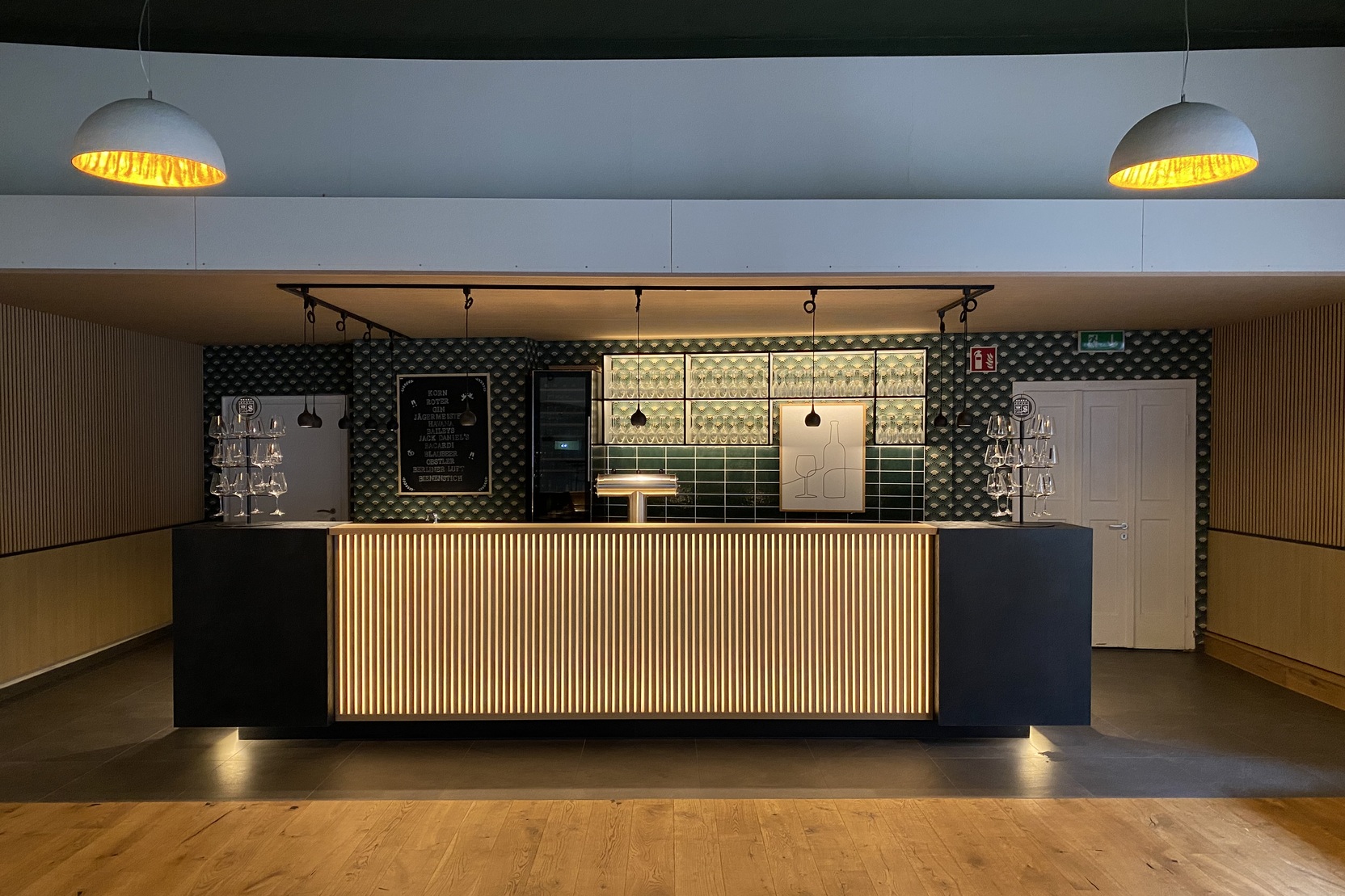 Moderne Empfangstheke in einem hellen Raum mit Holzfu&szlig;boden und stilvollen Lampen &uuml;ber der Theke.