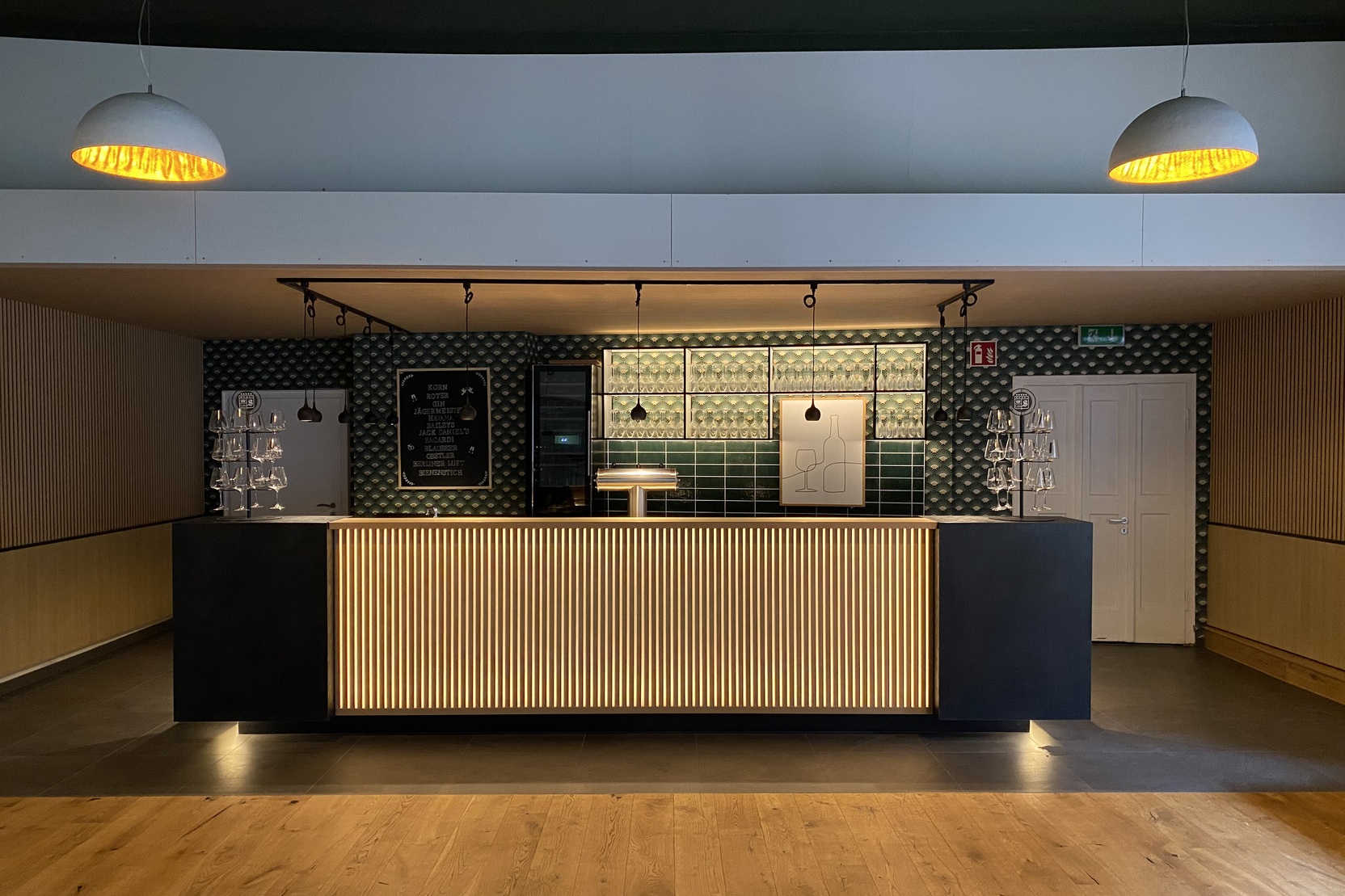 Moderne Empfangstheke in einem hellen Raum mit Holzfu&szlig;boden und stilvollen Lampen &uuml;ber der Theke.