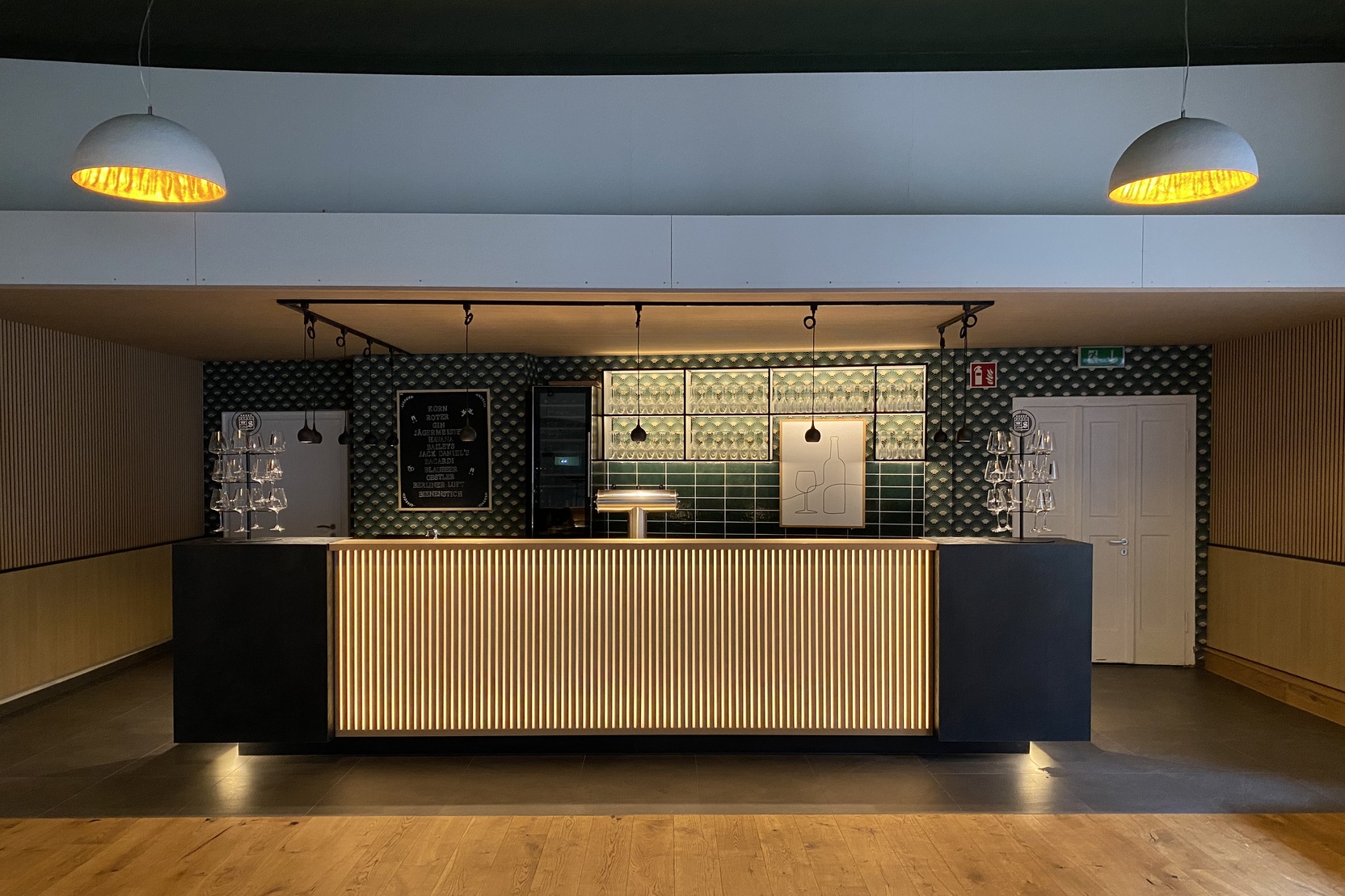 Moderne Empfangstheke in einem hellen Raum mit Holzfu&szlig;boden und stilvollen Lampen &uuml;ber der Theke.