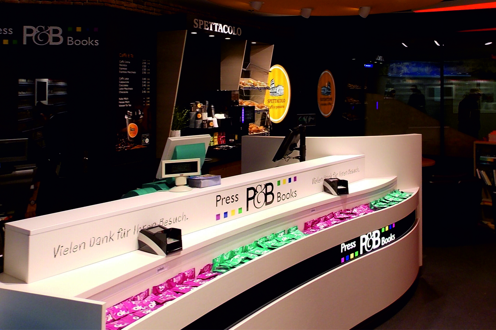 Moderne Verkaufsanordnung mit zwei Theken und farbiger Beleuchtung in einem Buchladen.
