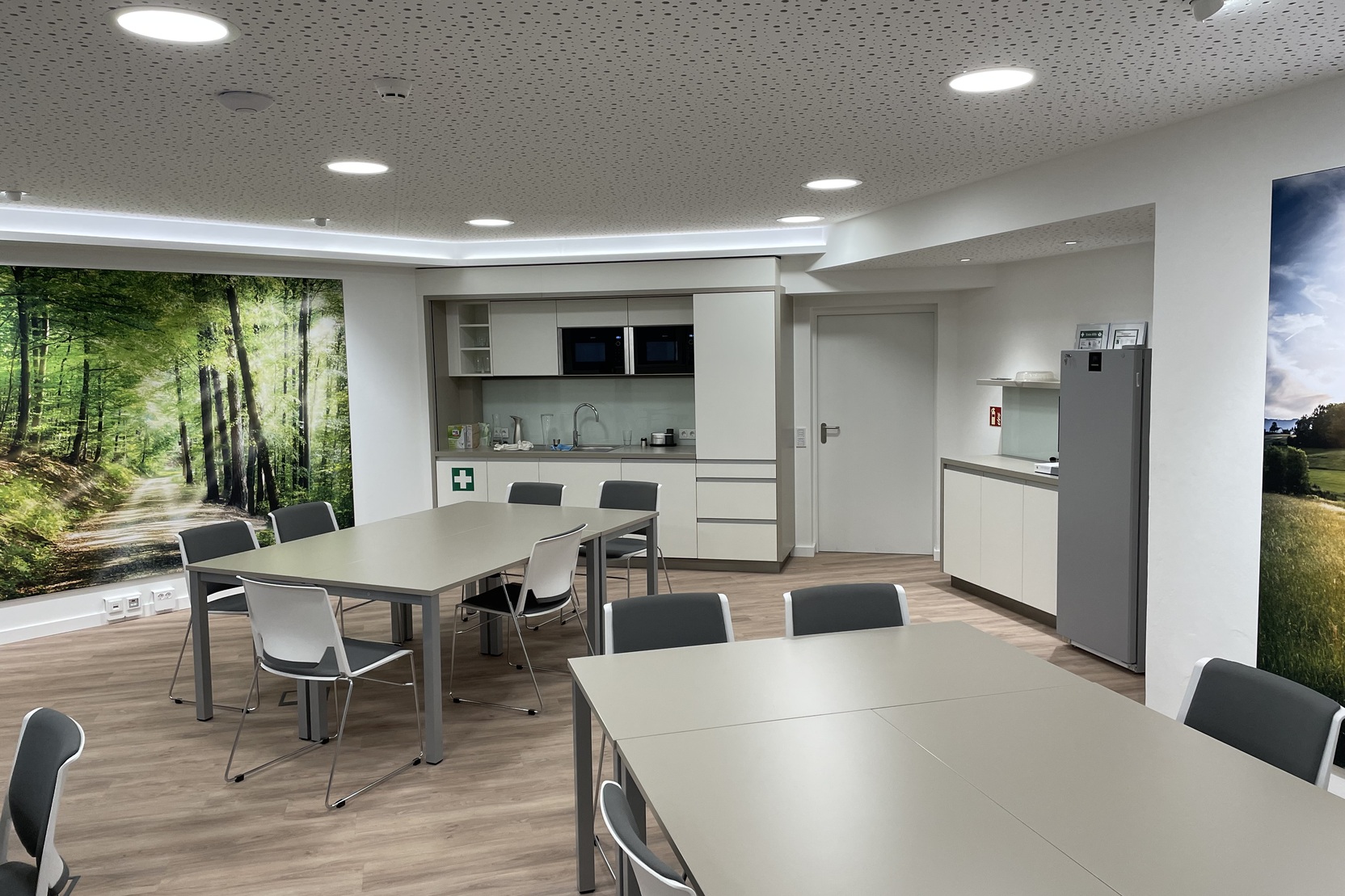 Moderne Teek&uuml;che mit Tisch und St&uuml;hlen in einem Raum mit Wandbild eines Waldpfades.