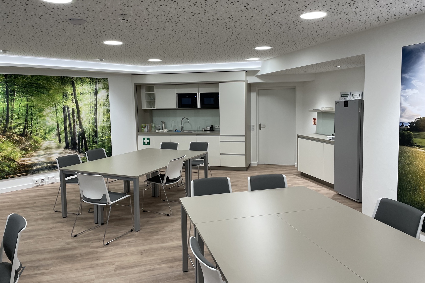 Moderne Teek&uuml;che mit Tisch und St&uuml;hlen in einem Raum mit Wandbild eines Waldpfades.