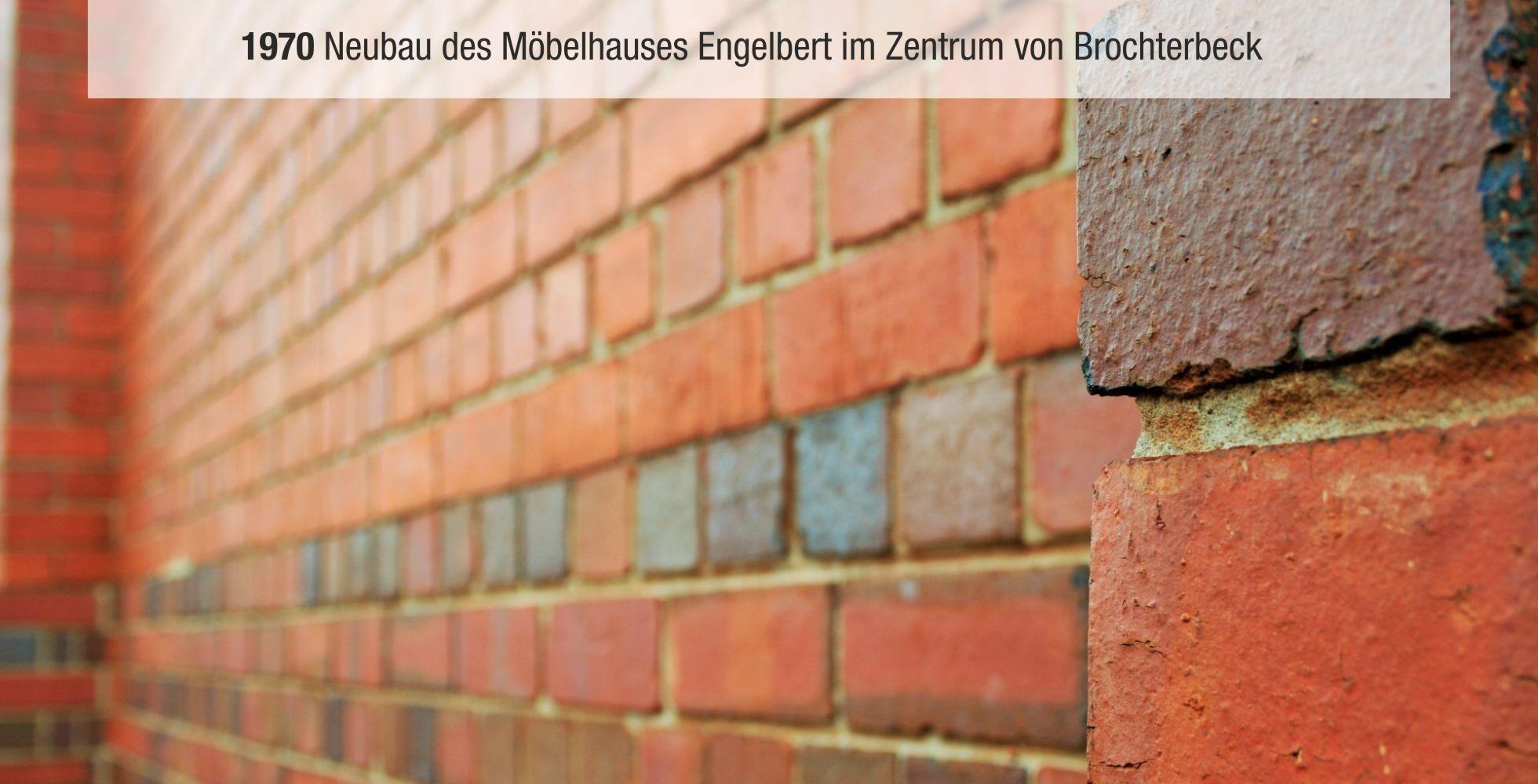 Detailaufnahme einer Ziegelmauer, mit farblich unterschiedlichen Ziegelsteinen, im Hintergrund eine Beschriftung.