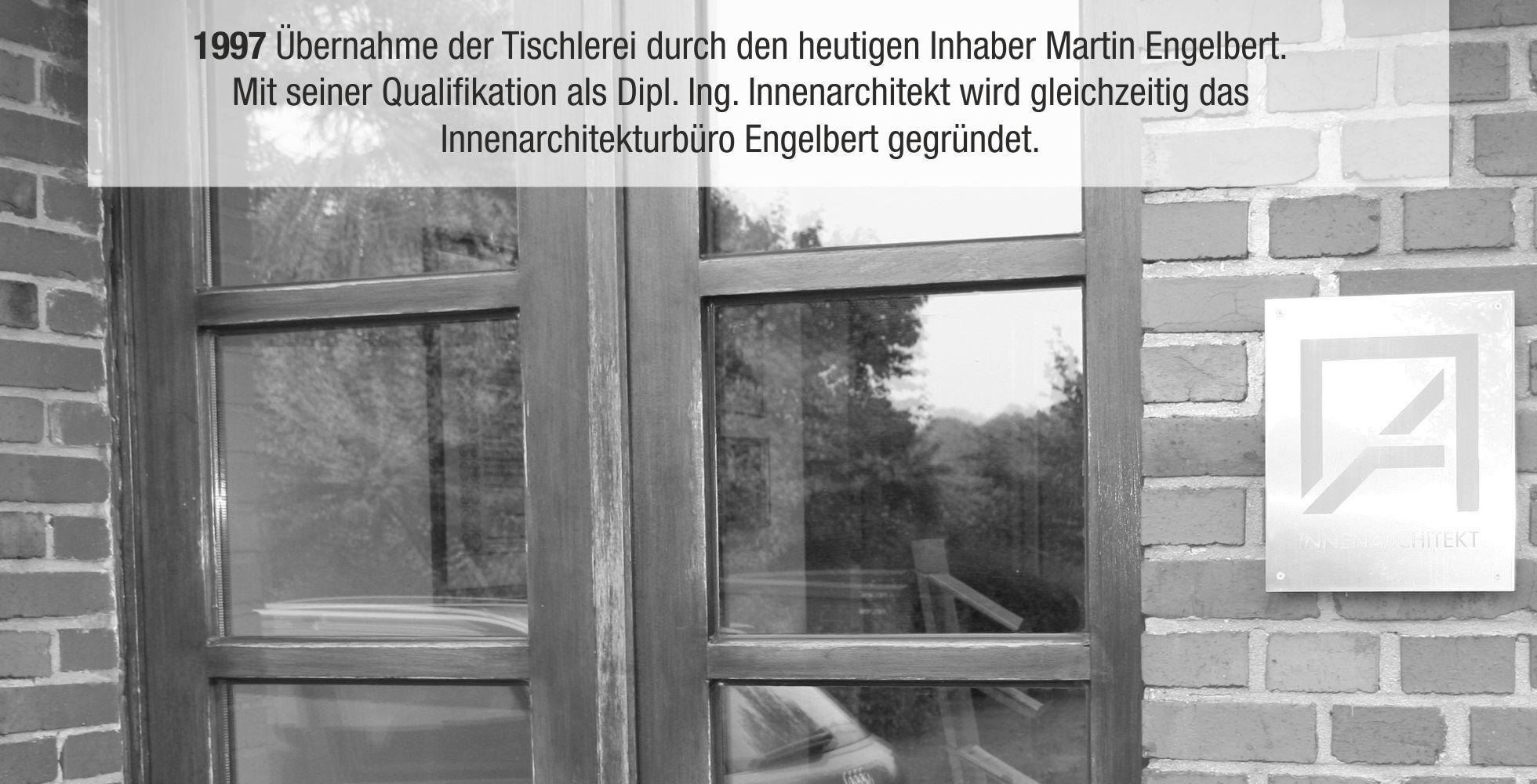 Eingang zu einer Tischlerei mit Holzt&uuml;ren und einem Schild des Innenarchitekturb&uuml;ros Engelbert in Schwarz-Wei&szlig;.