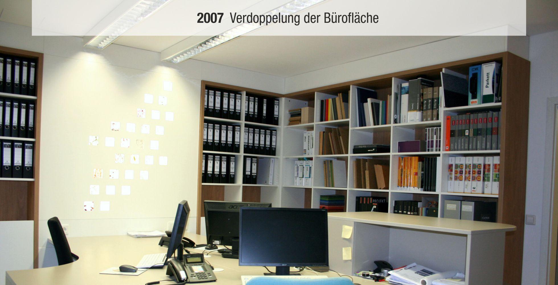 B&uuml;roansicht mit Schreibtisch, Computer und Regalen voller Aktenordner, Beschriftung &bdquo;2007 Verdopplung der B&uuml;rofl&auml;che&ldquo;.