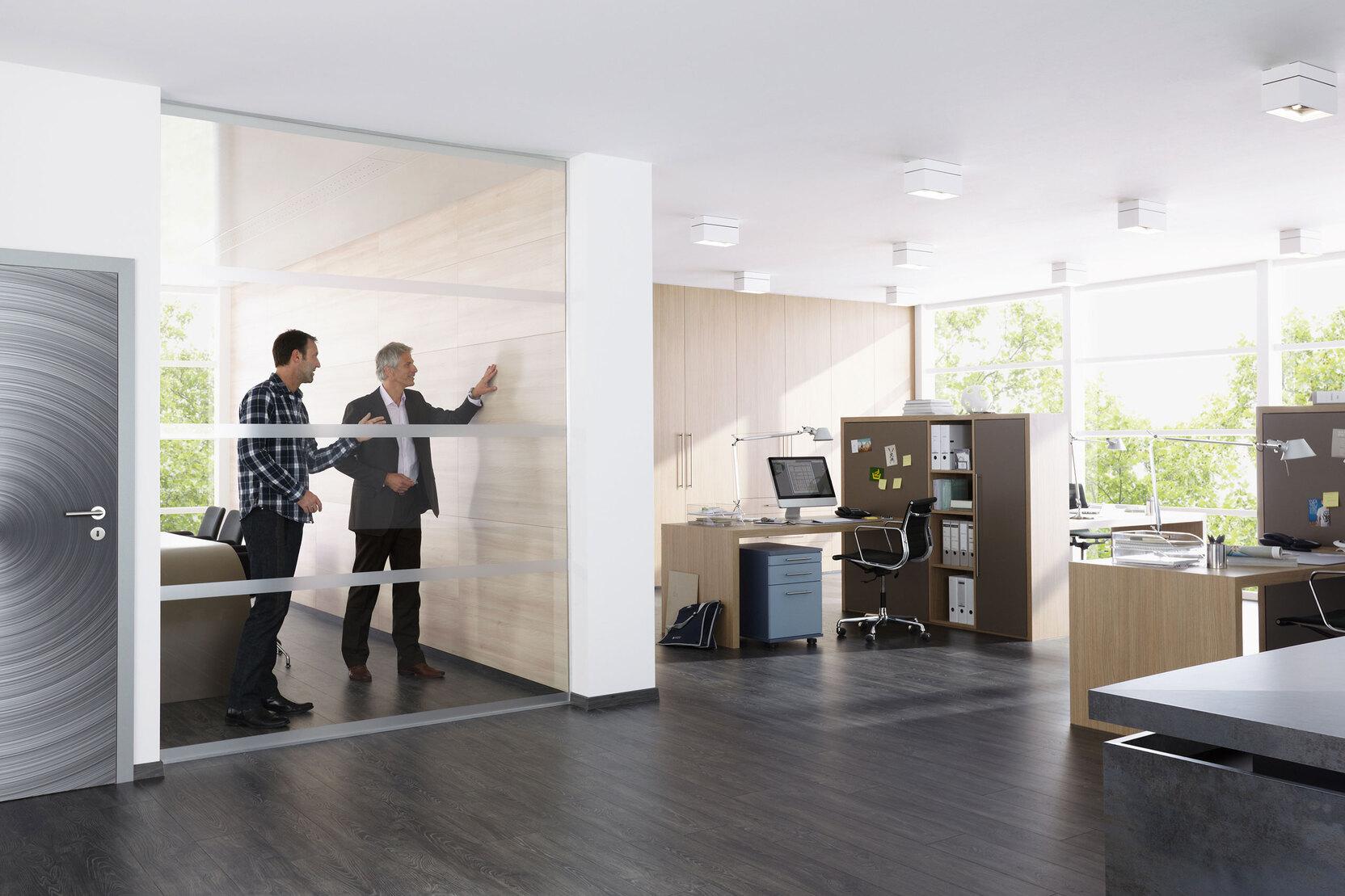 Impression eines Büros mit abgeschlossenem Raum mit Glaswand und offener Bürogestaltung.