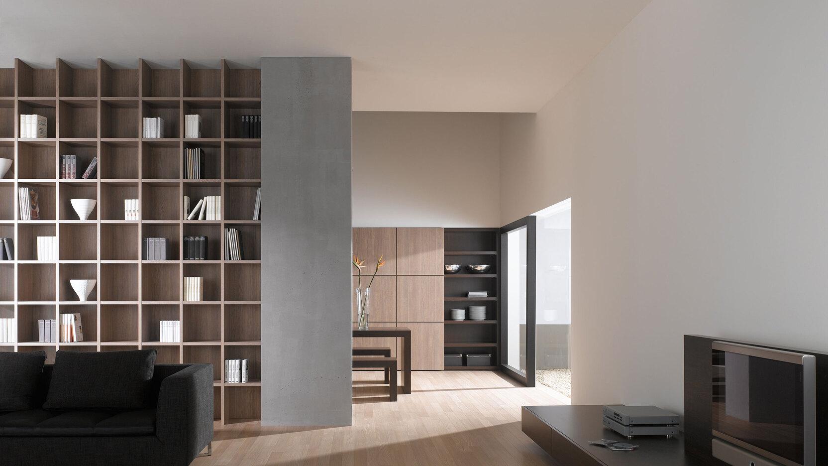Offene Wohnraumimpression mit Einbauregal in Trennwand Offene Wohnraumimpression mit Einbauregal für Bücher und Dekoration in Trennwand mit hellem Holzboden