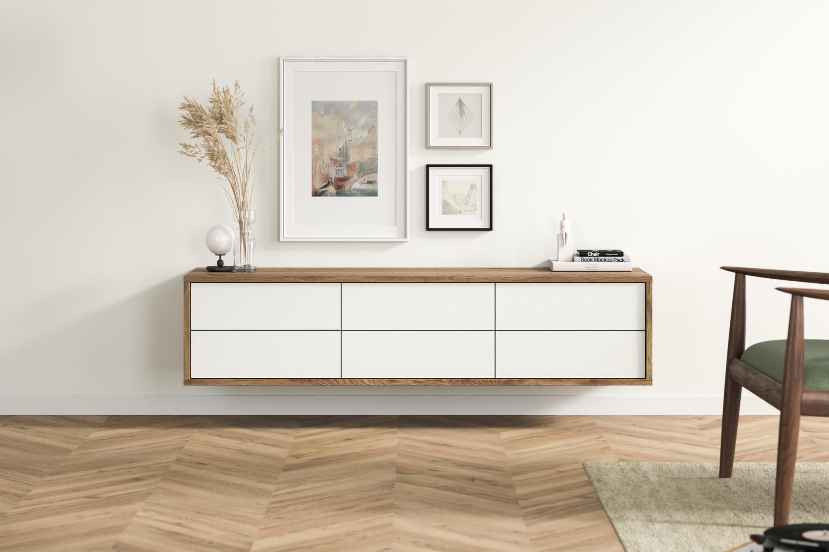 Maßgefertigtes Hängeboard im modernen Wohnbereich Ein minimalistisches, maßgefertigtes Hängeboard aus Holz mit weißen Schubladen, unter eingerahmten Bildern, verleiht diesem Wohnbereich ein stilvolles Flair.